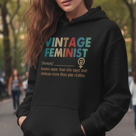 Woman wearing a black hoodie with 'VINTAGE FEMINIST' text in a park