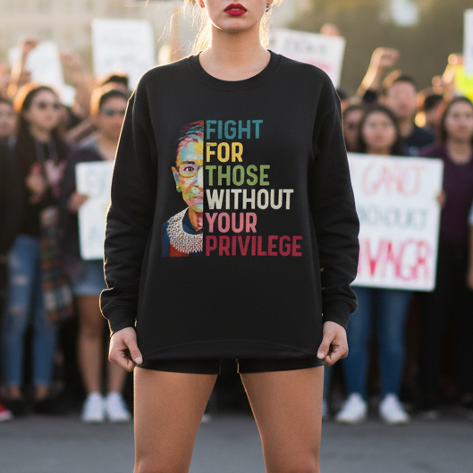Woman standing in front of a protest crowd wearing a black sweatshirt with colorful text. Fight for those without your privilege
